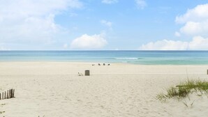 Ein weiter Sandstrand mit blauem Himmel und ruhiger See.
