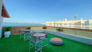 A rooftop terrace with green artificial grass, seating areas, and a view of the sea. - Mirante-506 - Apt 300m From the Beach by Carpediem (Fortaleza)