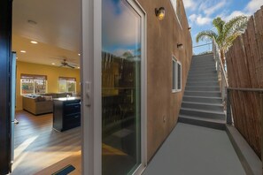 Ein modernes Haus mit Glastür, die in einen Wohnbereich, eine Küche und eine Treppe führt.