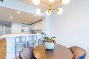 Une cuisine moderne avec des meubles blancs, un îlot central et un coin repas comprenant deux chaises et une table.