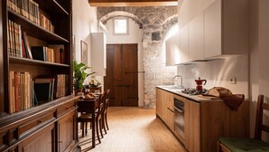 Una cocina compacta con armarios de madera, una mesa de comedor con sillas, una pared de piedra y una ventana.