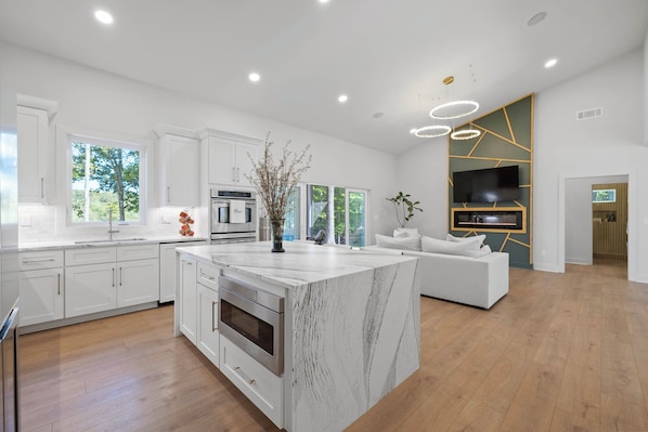 A modern kitchen with white cabinetry, a large island, and a built-in oven.