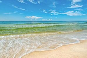 Una playa con agua azul cristalina y una orilla arenosa.