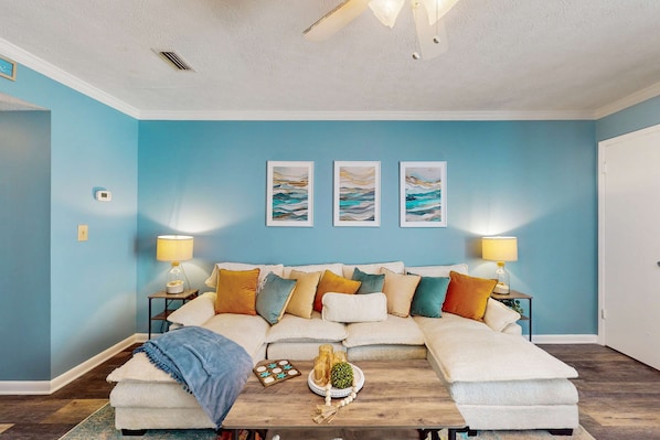 Una sala de estar acogedora con una pared azul, un conjunto de sofás, una mesita de centro y dos lámparas.