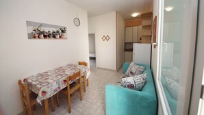 A compact living space with a dining table, a sofa, and a kitchen area. - Rosolina Mare Flat Near Beach (Rosolina)