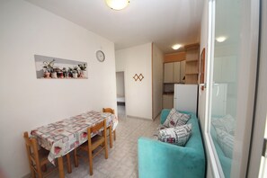 A compact living space with a dining table, a sofa, and a kitchen area. - Rosolina Mare Flat Near Beach (Rosolina)