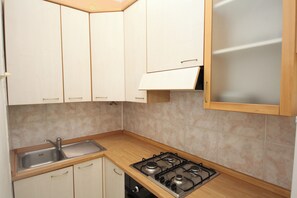 A kitchen with white cabinets, a stainless steel sink, and a gas stove. - Rosolina Mare Flat Near Beach (Rosolina)
