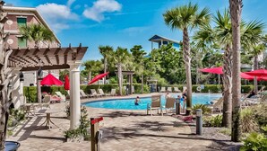 A pool area with lounge chairs, palm trees, and a pergola. - Elegant condo with 2 community pools, hot tub, & beach access across the road (Seacrest)