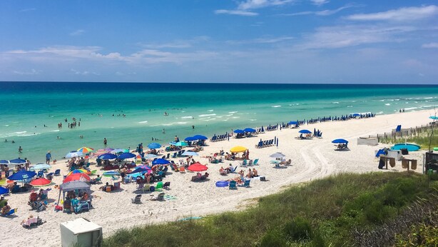 A beach with numerous umbrellas and beach chairs, a sandy shore, and the ocean in the background. - Elegant condo with 2 community pools, hot tub, & beach access across the road (Seacrest)