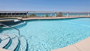 A clear blue pool with a modern design, a poolside area with lounge chairs, and a view of the ocean. - Stunning Florida getaway with Gulf view, pools, & central location (Panama City Beach)
