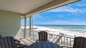 A wooden deck with a view of a beach and ocean.