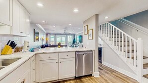 A modern kitchen with white cabinets, a stainless steel dishwasher, and a wooden floor. - Oceanfront Townhouse w/ Ocean Views, High-Speed WiFi, Washer/Dryer, & Central AC (Panama City Beach)