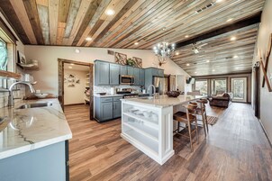 Una cocina amplia con piso de madera, una isla central y gabinetes grises.