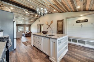 Una cocina moderna con una isla central, techo de madera y una araña.