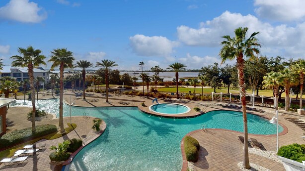 A resort with a large pool area, palm trees, and a view of the water. - 3rd-floor beach view condo with Pool, Hot tub, & private balcony (Panama City Beach)
