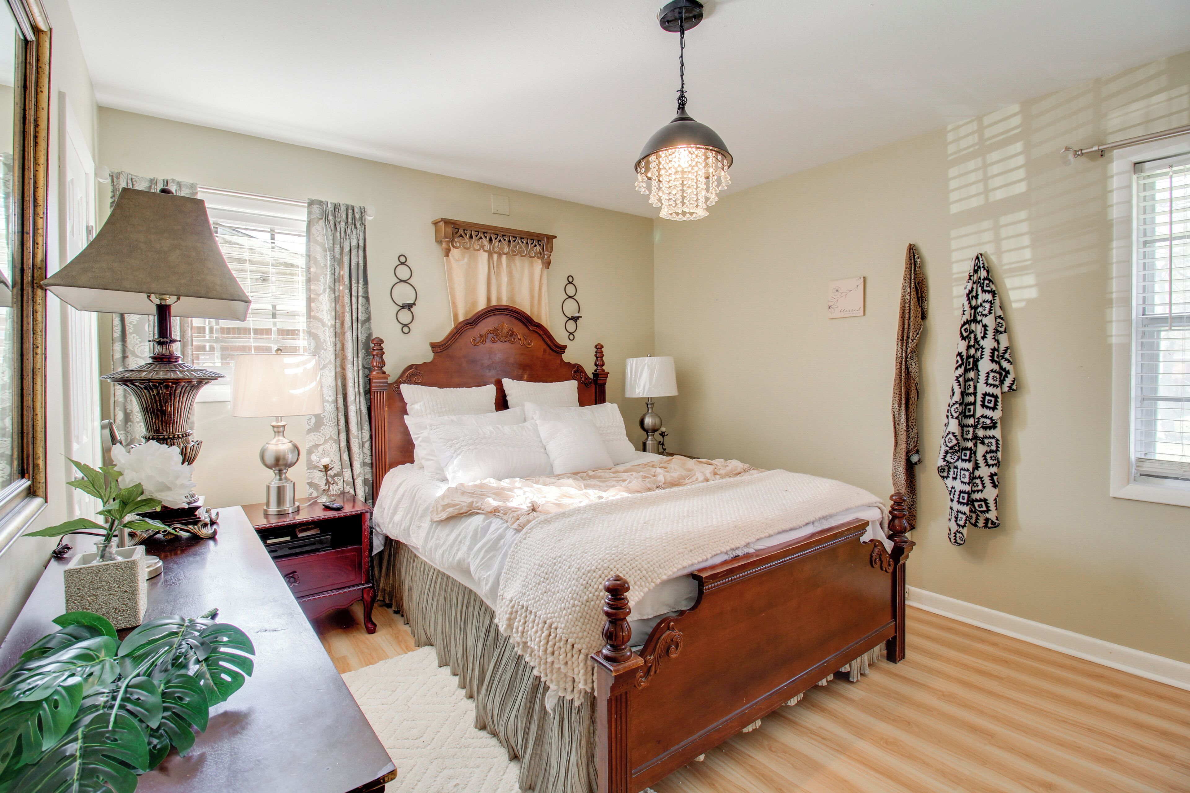 A bedroom with a wooden bed, bedside tables, a lamp, and a hanging light fixture.