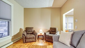 A living room with a wooden floor, two leather armchairs, a grey sofa, and a small table with a lamp. - Stay & Play in Ellicottville Village! Home w/ Deck (Ellicottville)