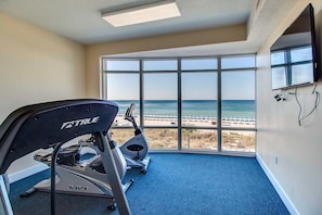 A gym with a view of the beach, a treadmill, and a stationary bike. - Waterfront condo in a resort setting w/ shared pools, hot tub, & beach access (Panama City Beach)