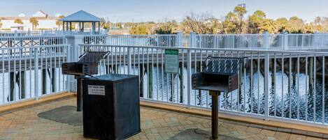 A covered outdoor area with a metal railing, a gazebo, and two grill stations.