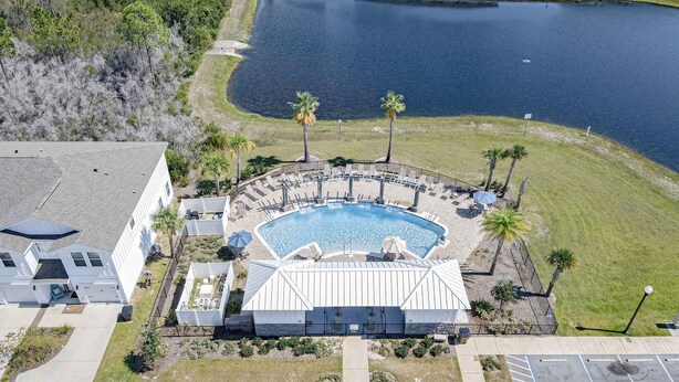 Vista aérea de un hotel con piscina, rodeado de palmeras y un lago.