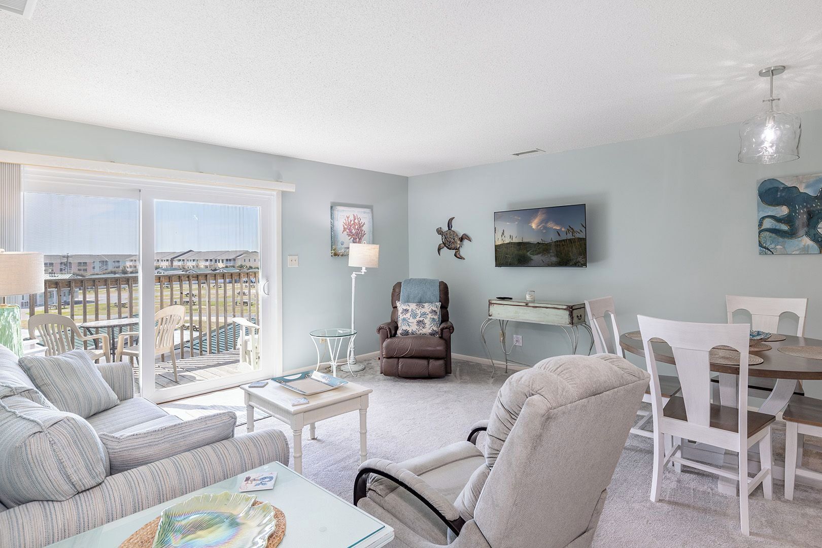 A spacious living room with a balcony, a dining area, and a cozy seating arrangement.