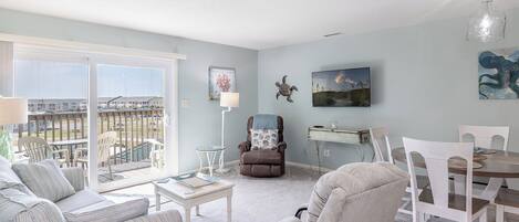 A spacious living room with a balcony, a dining area, and a cozy seating arrangement.