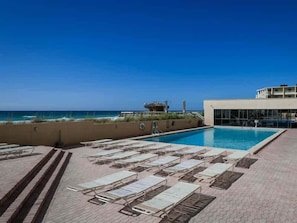 A pool area with lounge chairs and a view of the ocean. - Spacious 18th floor condo w amazing views - shared pool, hot tub, & central AC (Destin)