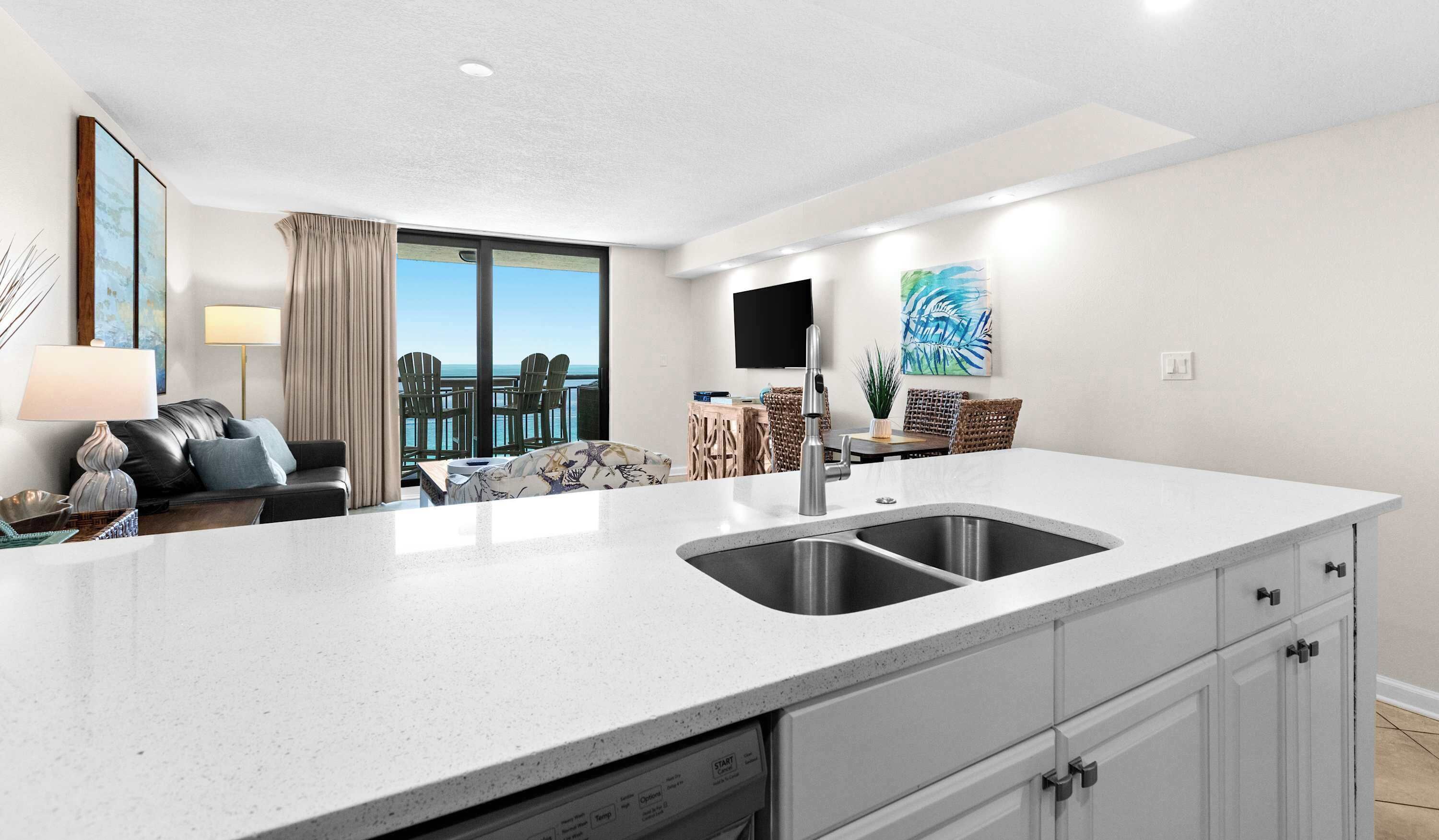 A modern kitchen with a large island, built-in dishwasher, and a view of the ocean.