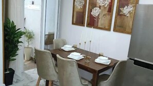 A dining area with a wooden table, four chairs, and a refrigerator. There are three framed floral paintings on the wall. - F2 high standings (Béjaïa)