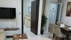 A modern living room with a sofa, a coffee table, and a flat-screen TV mounted on the wall. - F2 high standings (Béjaïa)