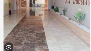 A spacious hallway with a polished marble floor, a geometric ceiling design, and a wall with the name 'Residance Nad D'abeille'. - F2 high standings (Béja ïa)