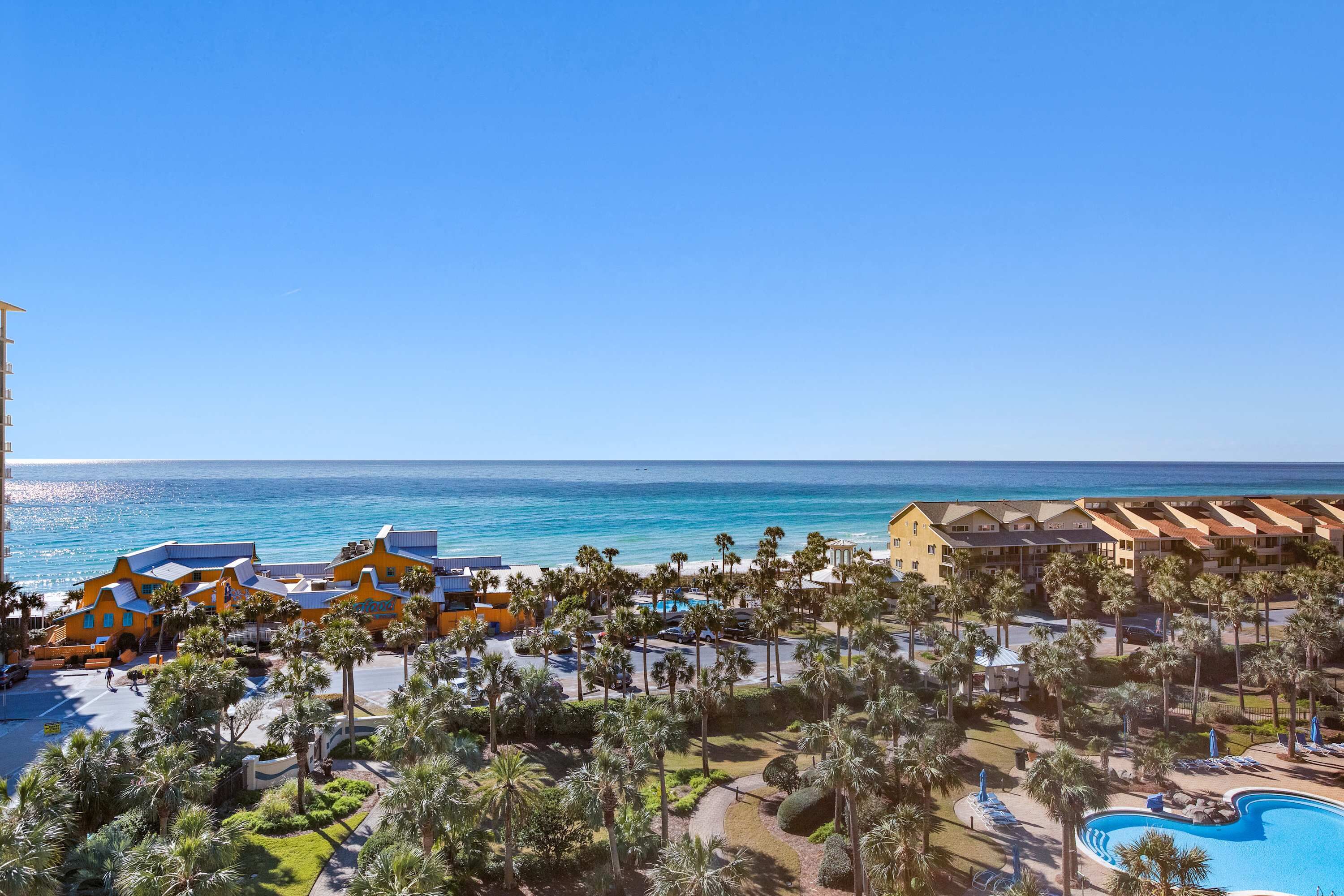 Un resort con piscina, palmeras y vista al océano.