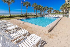 A swimming pool with lounge chairs and palm trees. - Oceanview condo with pool, tennis courts, beach access, laundry, & balcony (Destin)