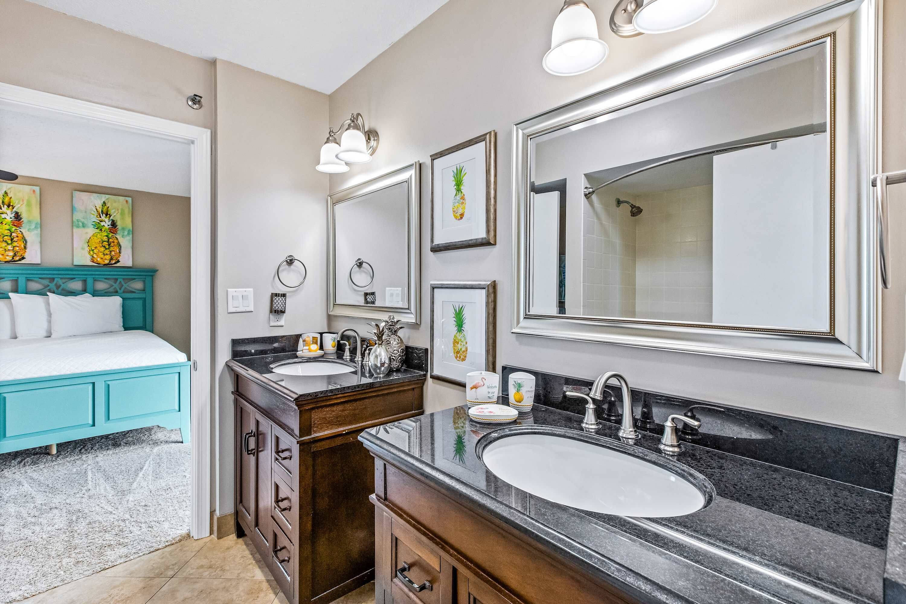 A modern bathroom with two sinks, a large mirror, and a bed with a teal headboard.