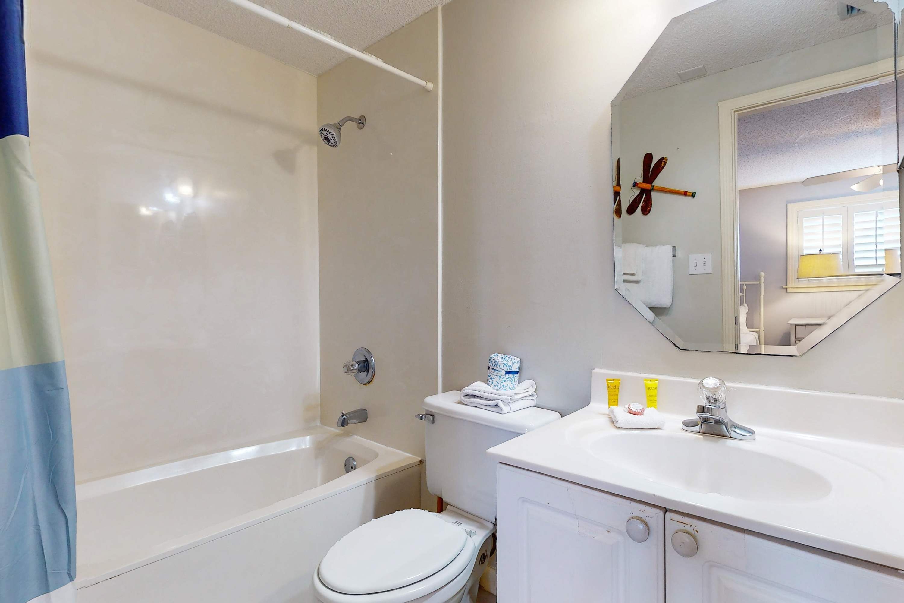 A bathroom with a bathtub, toilet, sink, and mirror.