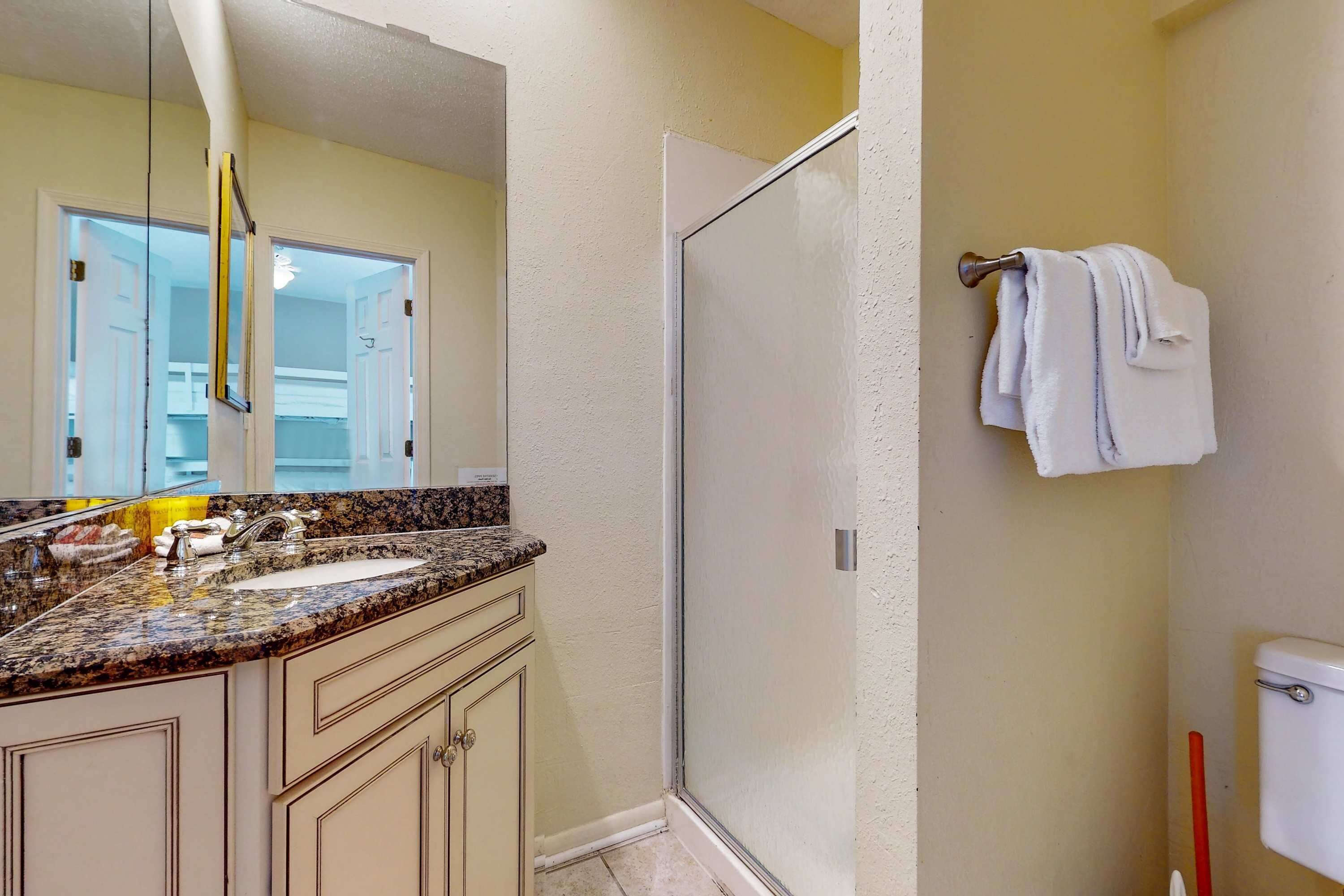 Un bagno con lavabo su piano in granito, box doccia in vetro e servizi igienici.