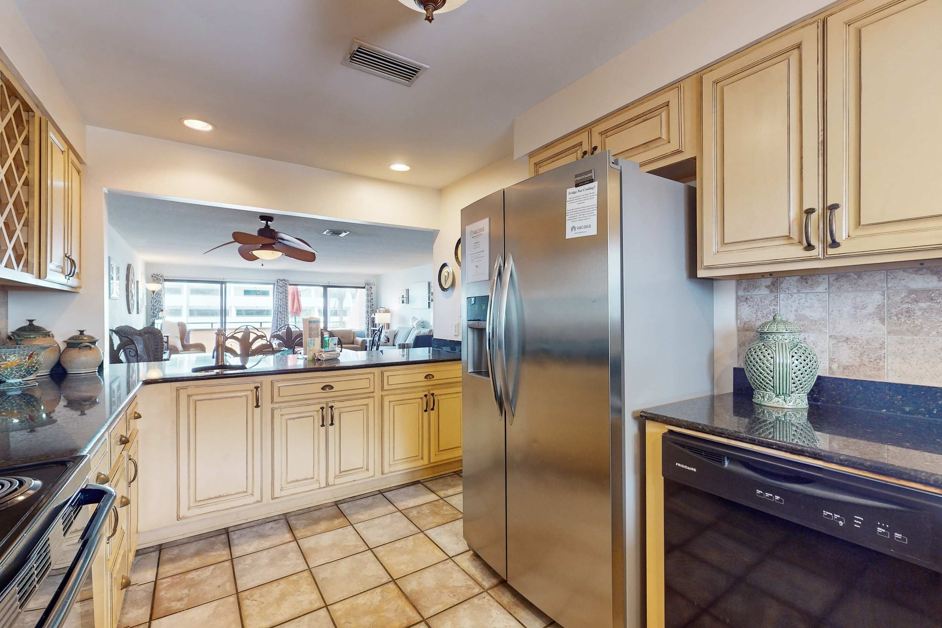 A modern kitchen with light-colored cabinets, a stainless steel refrigerator, and a dishwasher.