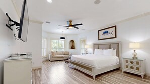 A bedroom with a bed, bedside tables, a ceiling fan, and a TV mounted on the wall. - Destiny West - Casa Isla Paraiso (Destin)
