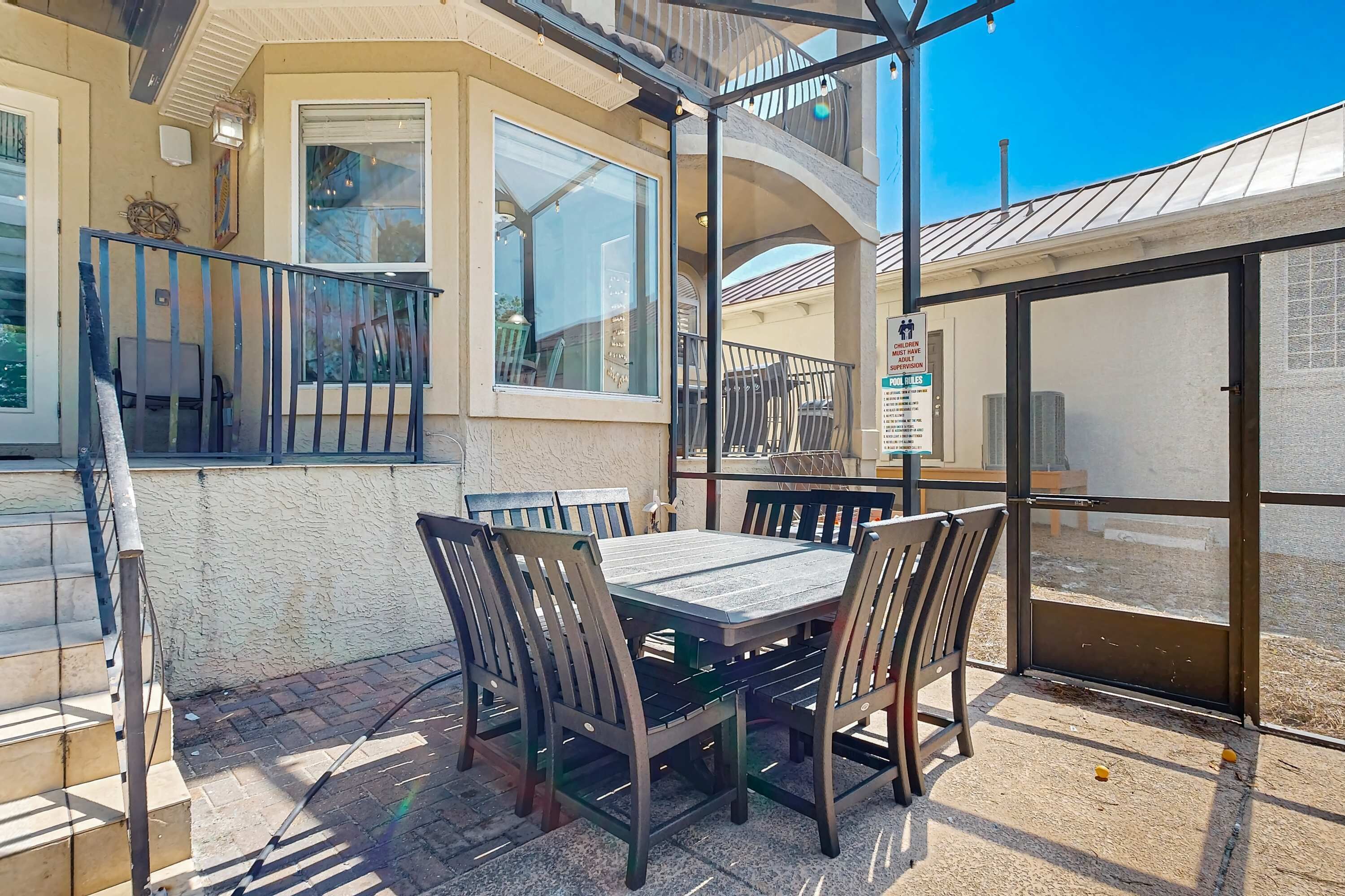 An outdoor patio with a table and chairs, a staircase, and a view of the surrounding area.
