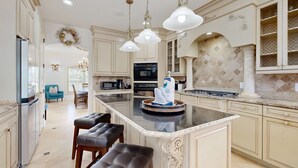 A spacious kitchen with a central island, pendant lighting, and a decorative backsplash. - Destiny West - Casa Isla Paraiso (Destin)