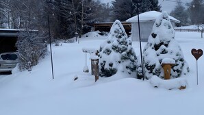 A snowy landscape with a garage, a snow-covered car, and a heart-shaped sign.