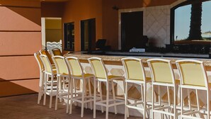 Un espace bar avec des chaises blanches et un comptoir.
