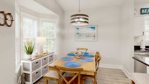 A dining area with a wooden table, blue placemats, and a hanging light fixture. - Dog-friendly home with pool, patio, & washer&dryer (Santa Rosa Beach)