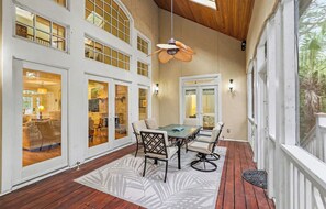 A spacious patio with a dining table and chairs, large windows, and a ceiling fan. - Pet Friendly, Chef's Kitchen, Exercise Room - 1 Fiddlers Point (Fripp Island)