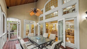 A spacious patio with a glass table and chairs, a ceiling fan, and a view of the interior through large windows. - Pet Friendly, Chef's Kitchen, Exercise Room - 1 Fiddlers Point (Fripp Island)