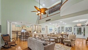 A spacious living room with a high ceiling, a dining area, and a kitchen. - Pet Friendly, Chef's Kitchen, Exercise Room - 1 Fiddlers Point (Fripp Island)