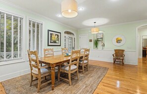 A dining area with a wooden table and chairs, a rug, and a hanging light fixture. - Pet Friendly, Chef's Kitchen, Exercise Room - 1 Fiddlers Point (Fripp Island)