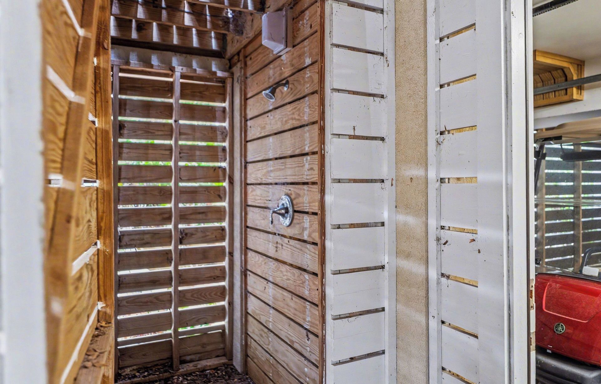 A narrow, enclosed space with wooden slats on one side and a white panel with horizontal lines on the other.