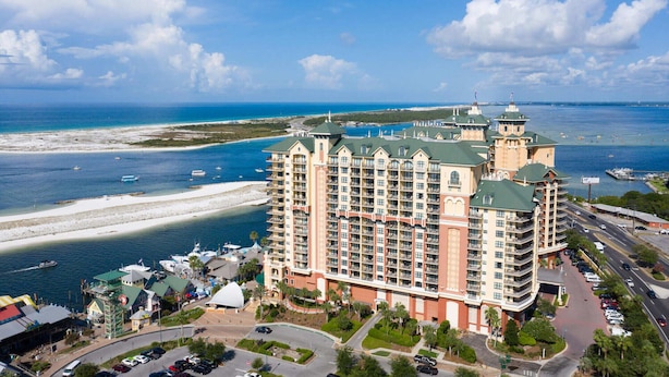 Een groot hotel met meerdere verdiepingen, een centraal torentje en uitzicht op het strand.