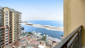 Een hoog hotel met meerdere balkons met uitzicht op een strand en water.